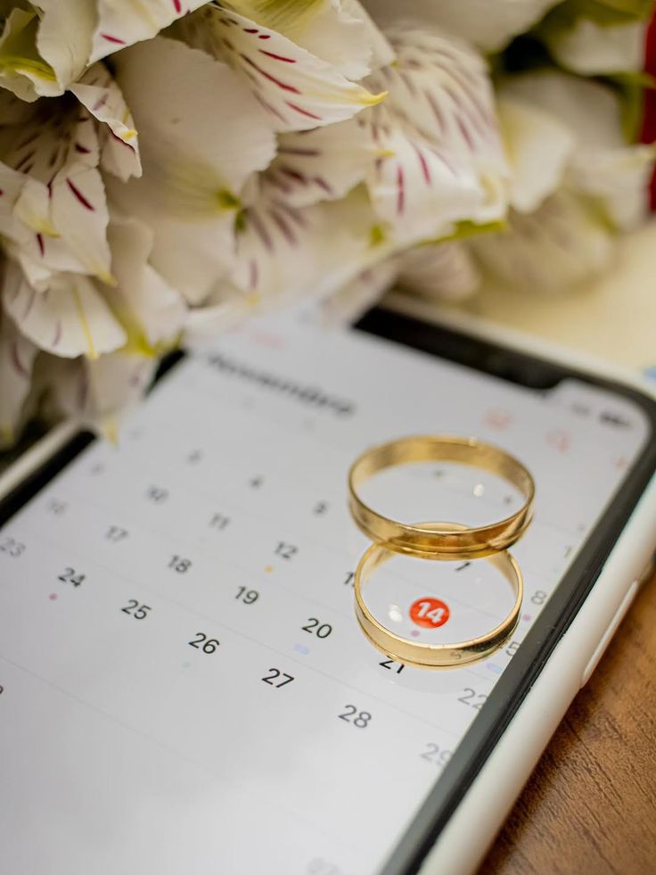 Alianças sobre um calendário e flores brancas — planejamento delicado do mini wedding